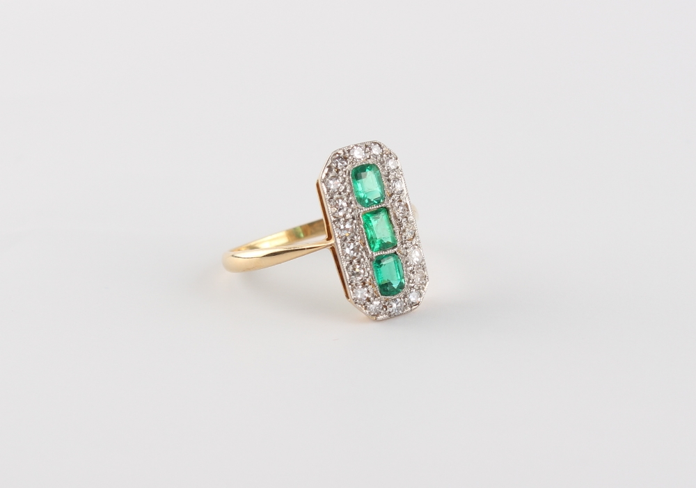 An Art Deco style yellow gold emerald & diamond ring, the elongated rectangular panel set with three