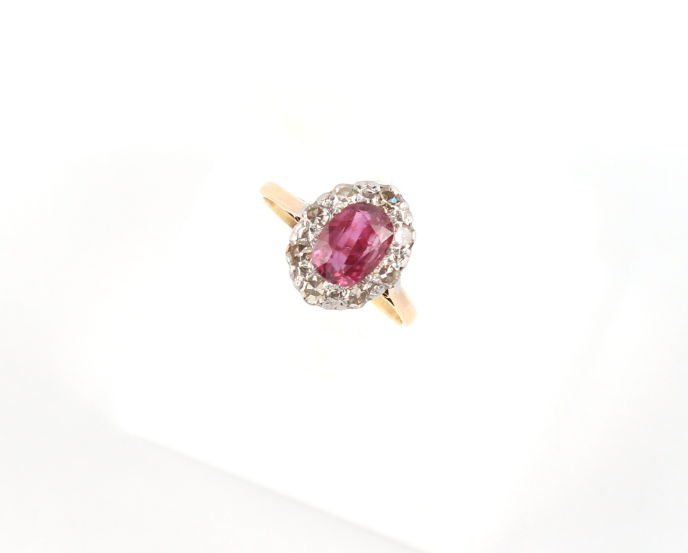 An 18ct yellow gold ruby & diamond oval cluster ring, the oval cushion cut ruby weighing
