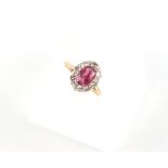 An 18ct yellow gold ruby & diamond oval cluster ring, the oval cushion cut ruby weighing