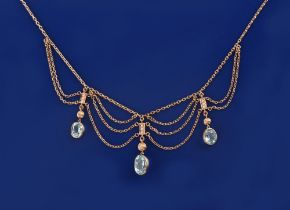 A yellow gold aquamarine festoon necklace, the largest of the three oval cut aquamarines measuring