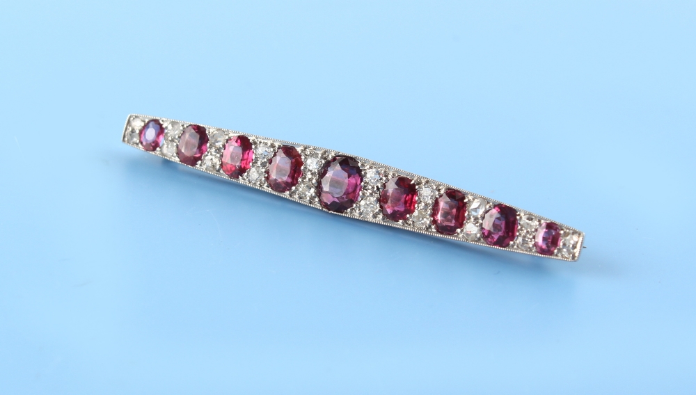 An Art Deco ruby & diamond long brooch, the nine oval cushion cut rubies weighing a total of