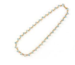 An unmarked yellow gold (tests 18ct) aquamarine riviere necklace, the thirty-six oval cut