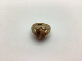 A 9ct Gold Tiger's Eye Single Stone Ring, oval cabochon claw set between satin polished shoulders (