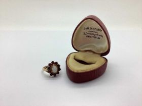 A 9ct Gold Garnet and Opal Set Cluster Ring, between tapered shoulders of scallop design, together