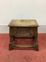 A XVII Century Style Joined Oak Box-Stool, with hinged lid, moulded edge and frieze with carved head