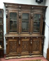 A XIX Century Carved Oak Bookcase, with a stepped pedestal over three glazed doors, the base with