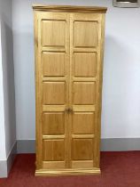A Beaverman Tall Bookcase, with twin panelled doors and panelled sides on a stepped plinth base,
