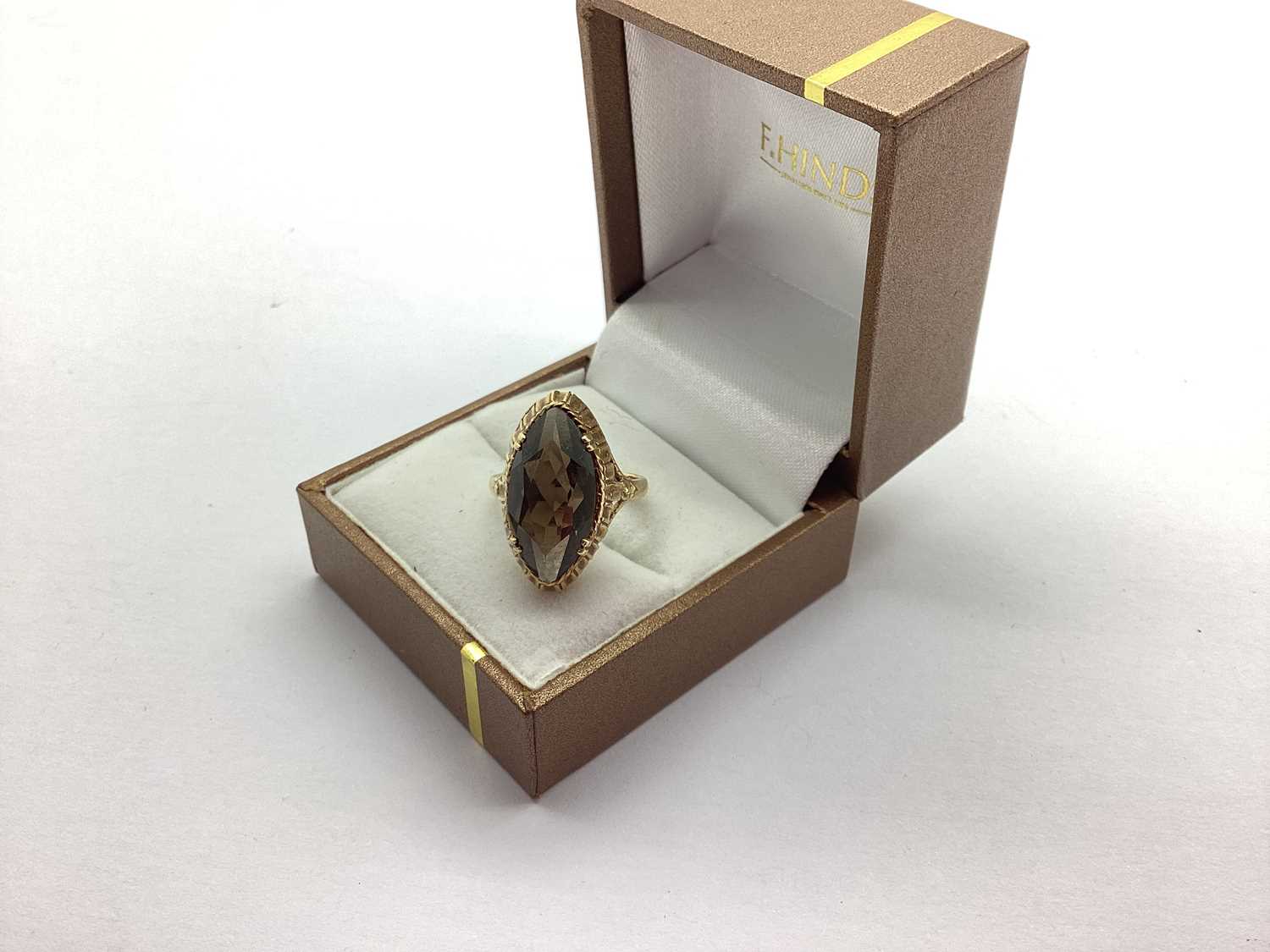 A 9ct Gold Dress Ring, with large claw set marquise cut stone, high textured setting, between