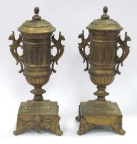 A pair of gilded brass vases with finial tops, twin handles as grotesque birds, on scroll feet, 30cm