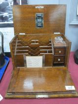 An early XX Century oak stationary and writing box with drop down front, ink well, drawers, calendar