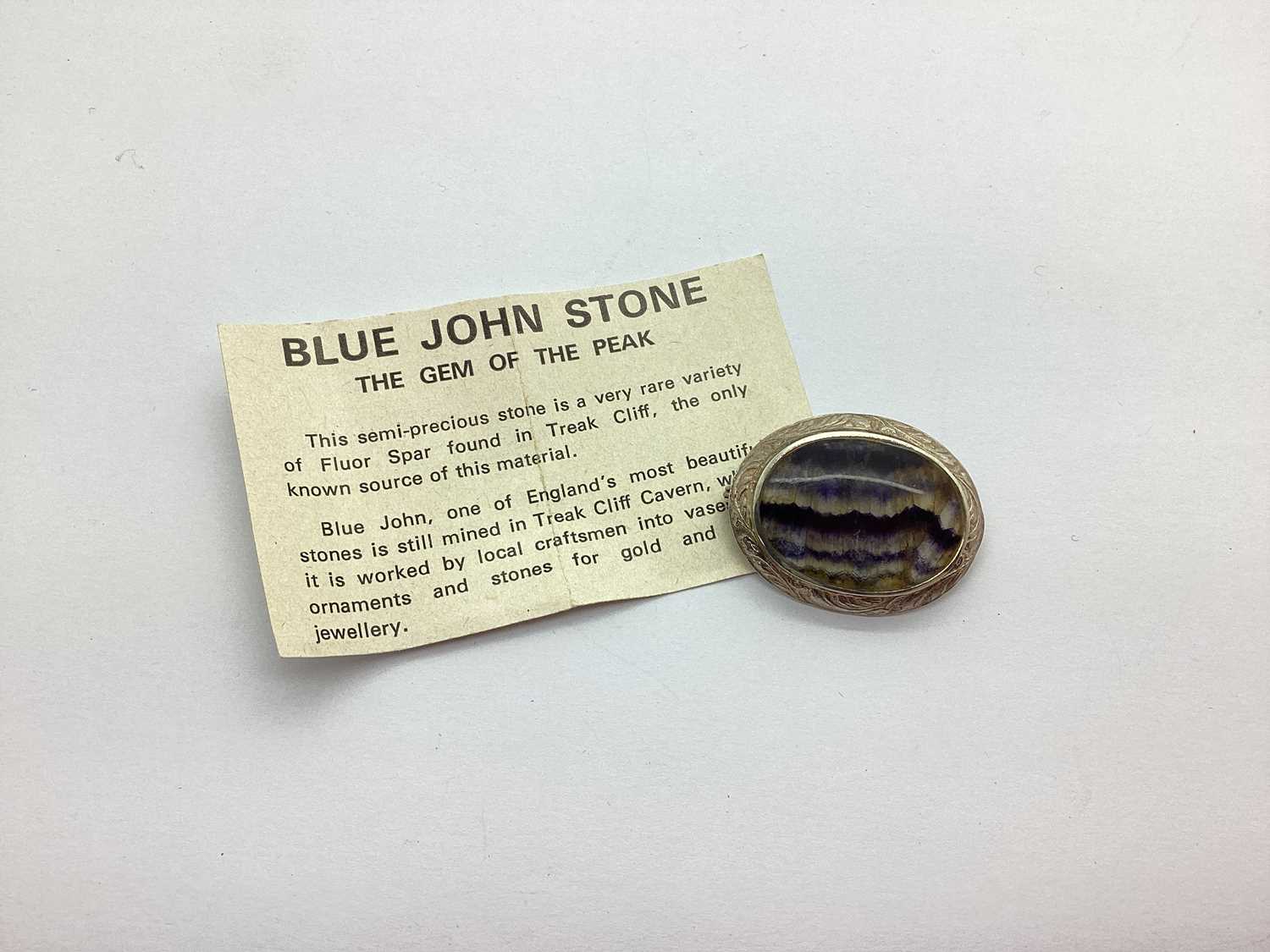 An Oval Blue John Panel Brooch, the textured mounted stamped "silver", 3.5cm long. Overall good