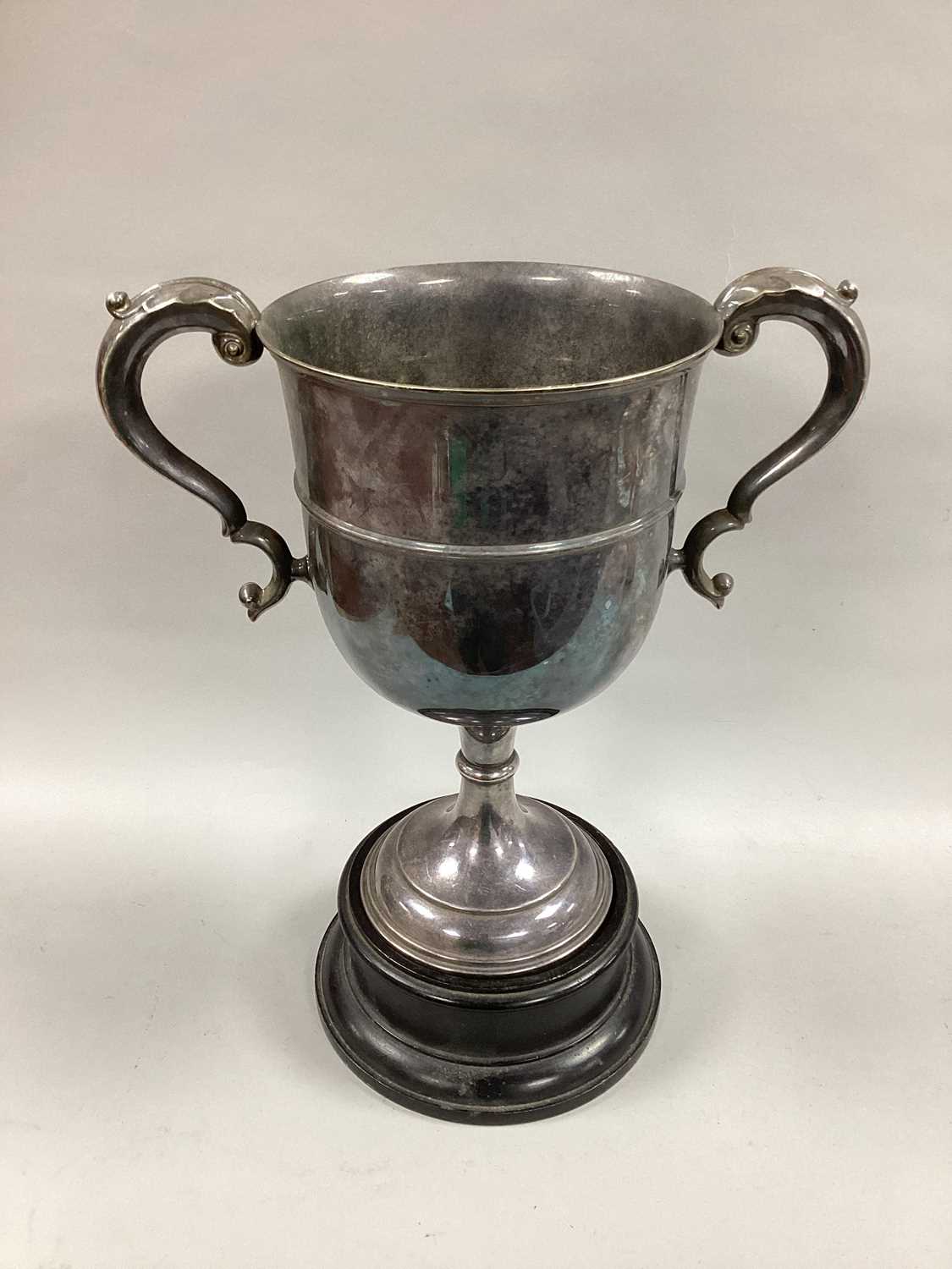 A Large Plated Twin Handled Trophy Cup, (no engraving) with leaf capped scroll handles, on black