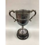 A Large Plated Twin Handled Trophy Cup, (no engraving) with leaf capped scroll handles, on black