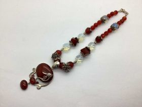 An Ornate Necklace, with alternate graduated beads, foliate detail, suspending a large oval polished