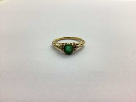 An 18ct Gold Emerald and Diamond Set Dress Ring, rectangular claw set to the centre, between claw