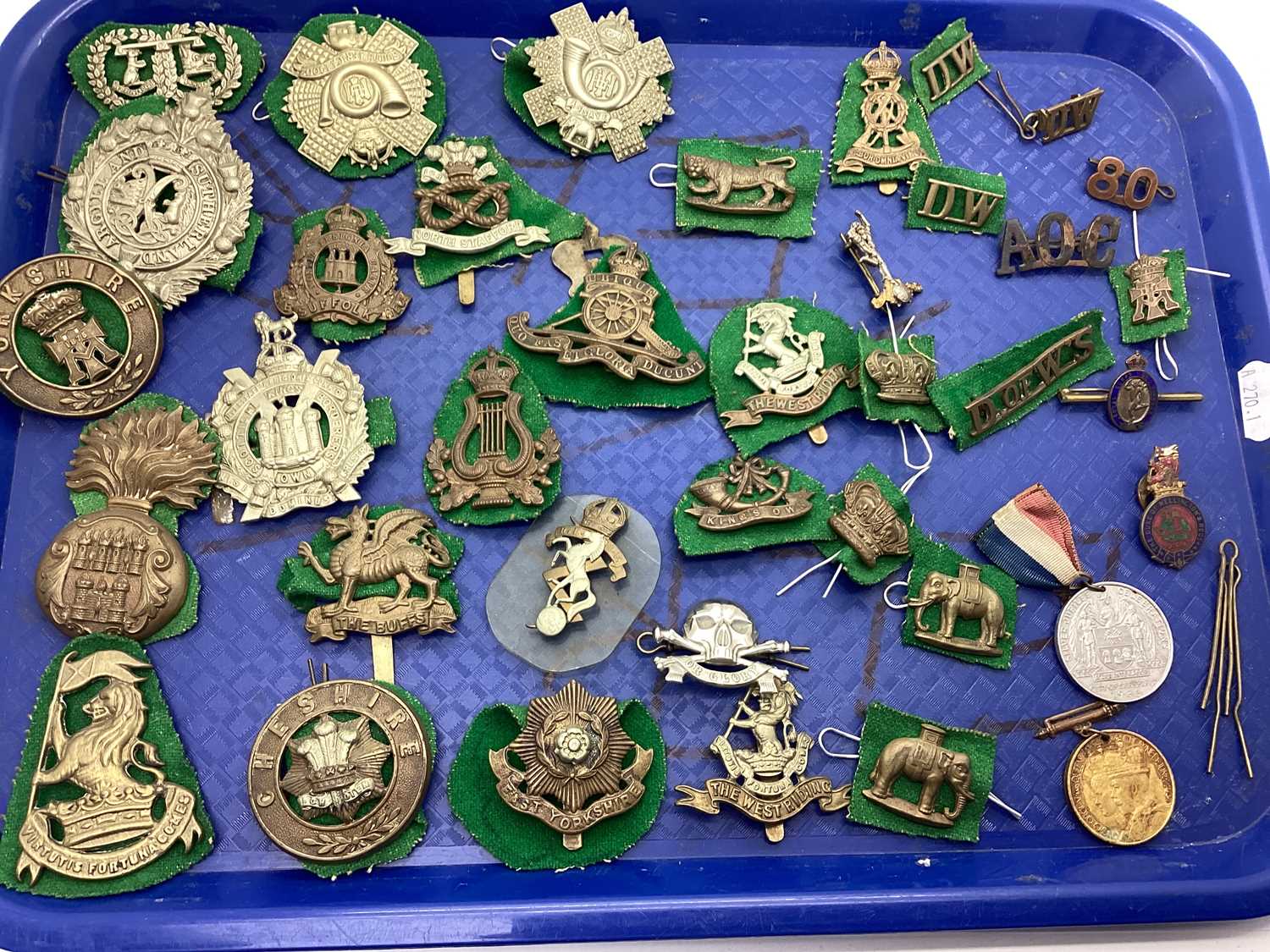 British Army cap badges and shoulder titles from various eras, including East Yorkshire Regiment,