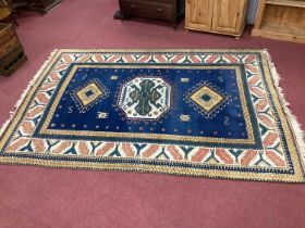 Middle Eastern Wool Tassled Carpet, with multicoloured geometric motifs on a blue centre panel and
