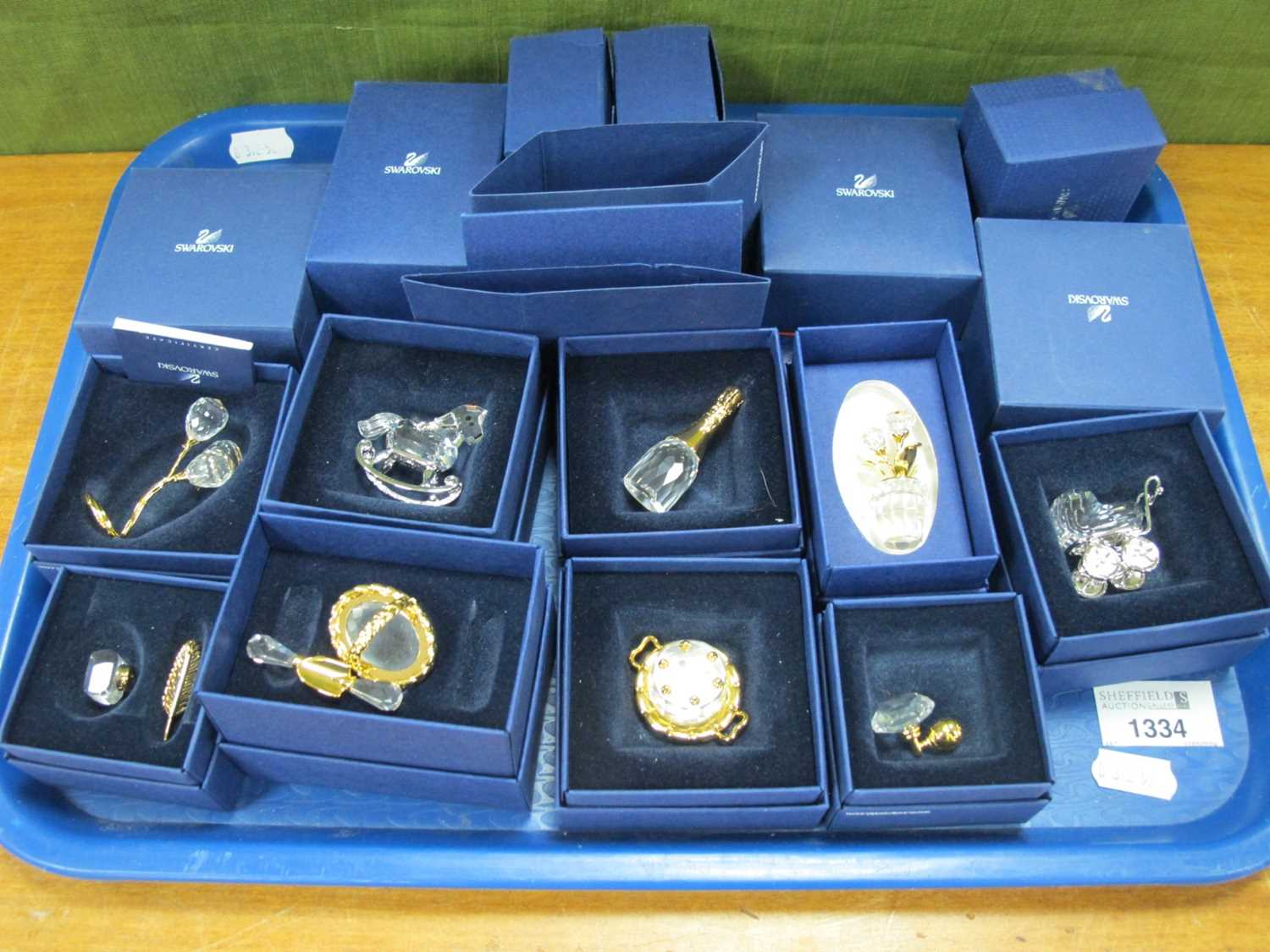 Nine Swarovski Crystal Miniatures, including pram, champagne bottle, plant pot, cake, garden tug,
