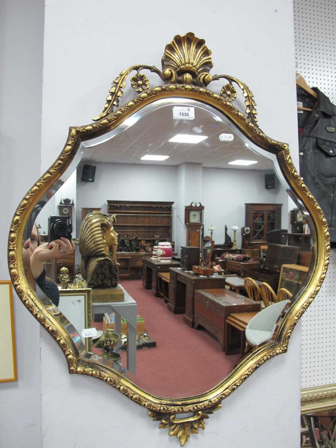 A XX Century Gilt Shaped Mirror, the top with shell decoration, the bottom with 'C' scroll