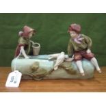 An Early XX Century Royal Dux Figure Group of a boy and girl with birds peering into a pond,