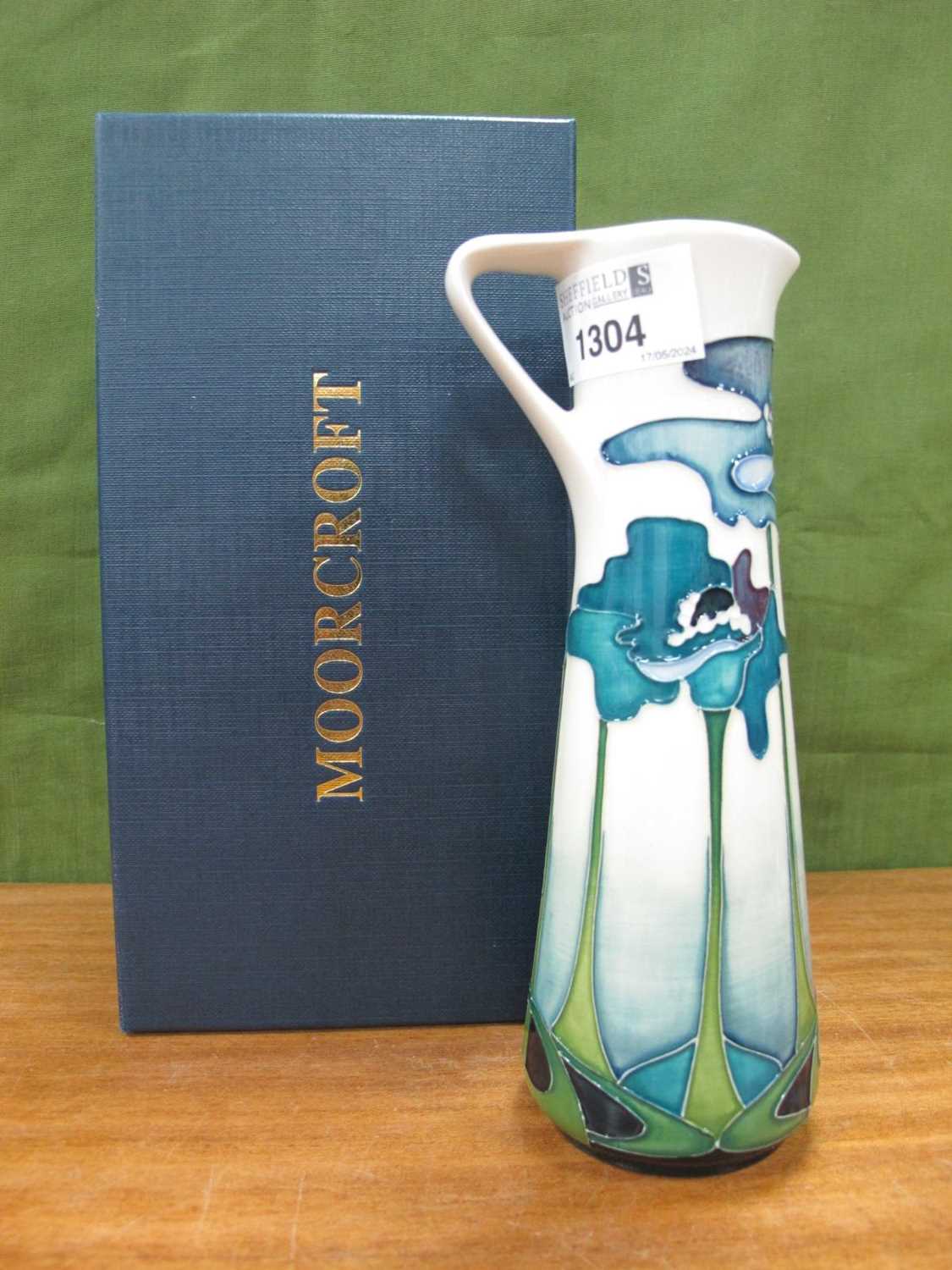 A Moorcroft Pottery Jug Vase, painted with a stylised blue poppy design on a cream ground, impressed