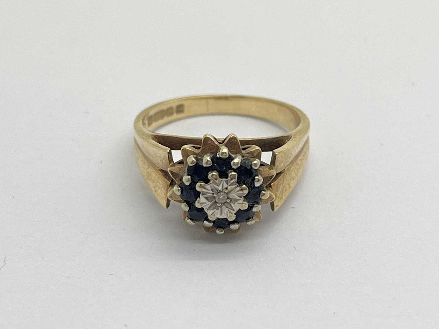 A 9ct Gold Vintage Brutalist Style Ring, the illusion set diamond to centre, between sapphire halo