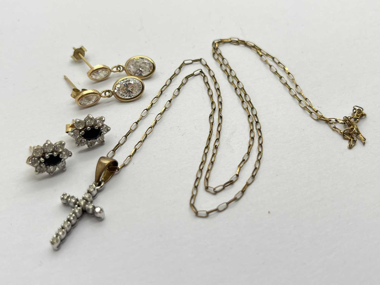 A 9ct Gold Stone Set Pendant, of cross design, claw set throughout, suspended on a dainty trace link