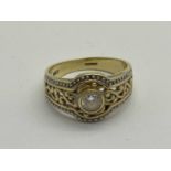 A 14ct Gold Two Tone Rubover Dress Ring, the round cut centre stone between ornate openwork band and