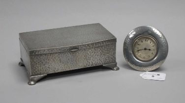 A Tudric Pewter Bedside Clock, the engine turned circular dial with black Arabic numerals, within