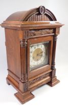 A Victorian walnut arch top architectural style mantel clock with pillar supports and silvered Art