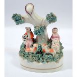 A small Victorian Staffordshire bocage group of seated couple with sheep and dog, 10.5cm