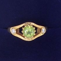 An 18 carat gold ring set peridot flanked by a pair of diamonds, size N, 6.5g