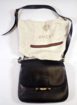 A vintage 1960's Gucci black leather handbag with gilt metal clasp, shoulder strap and purse, with