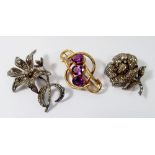 Two silver and marcasite flower form brooches and a Victorian gilt metal and purple glass brooch,