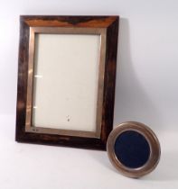 A small silver circular picture frame with easel back together with a larger hanging hardwood