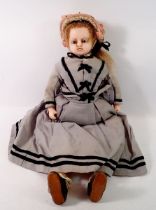 A Victorian wax doll with cloth body, wax arms and legs, original clothing, hat, shoes bolster