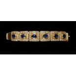 An 18 carat gold hinged bangle with six square panels set sapphires within diamond surround, total