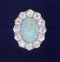 A large platinum opal and diamond cluster ring, the opal 12mm x 9mm, the twelve brilliant cut