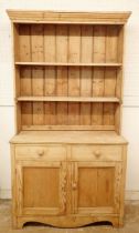 A 19th century large pine dresser with open shelves above two drawers and two cupboard doors,
