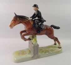 A Beswick huntswoman riding side saddle, taking a fence