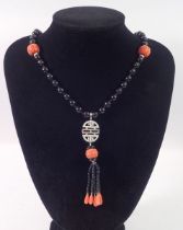 An Art Deco style 15ct white gold onyx and coral bead necklace with diamond set geometric drop and