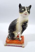 A Victorian Staffordshire cat seated on a cushion, 20cm