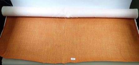 An long piece of orange woven upholstery fabric on a roll