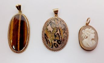 A 14 carat gold tigers eye pendant, a 9 carat gold stone pendant and a gold framed cameo - unmarked