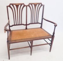 An Edwardian mahogany small settee or love seat with fret back and satinwood inlay