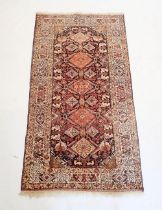 A Persian style rug with coral red and blue lozenge design, 181 x 100cm