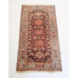 A Persian style rug with coral red and blue lozenge design, 181 x 100cm