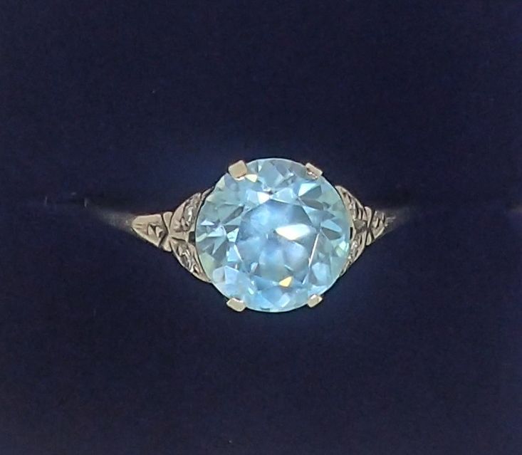 An 18 carat white gold ring set blue zircon on diamond chip shoulders, size P-Q, 2.6g