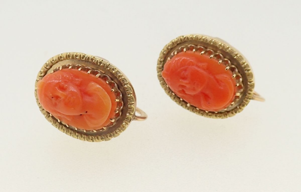 A pair of coral cameo screw back earrings in 10 carat gold mounts