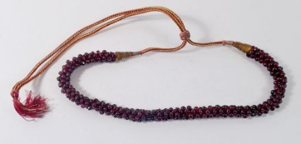 An Eastern garnet bead necklace with metallic thread fastener